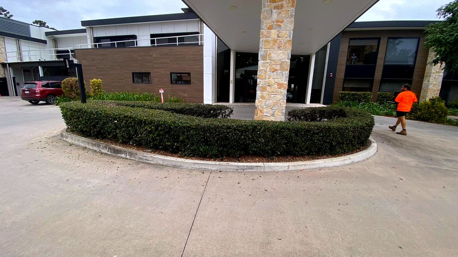 Broadfield crew member walking the grounds at a landscaped commercial building entrance