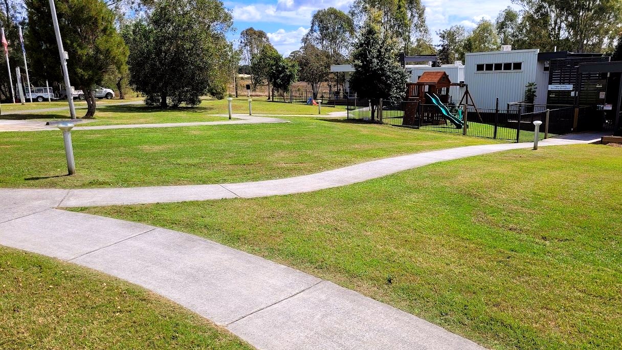 Mown school grounds with playground and shade trees